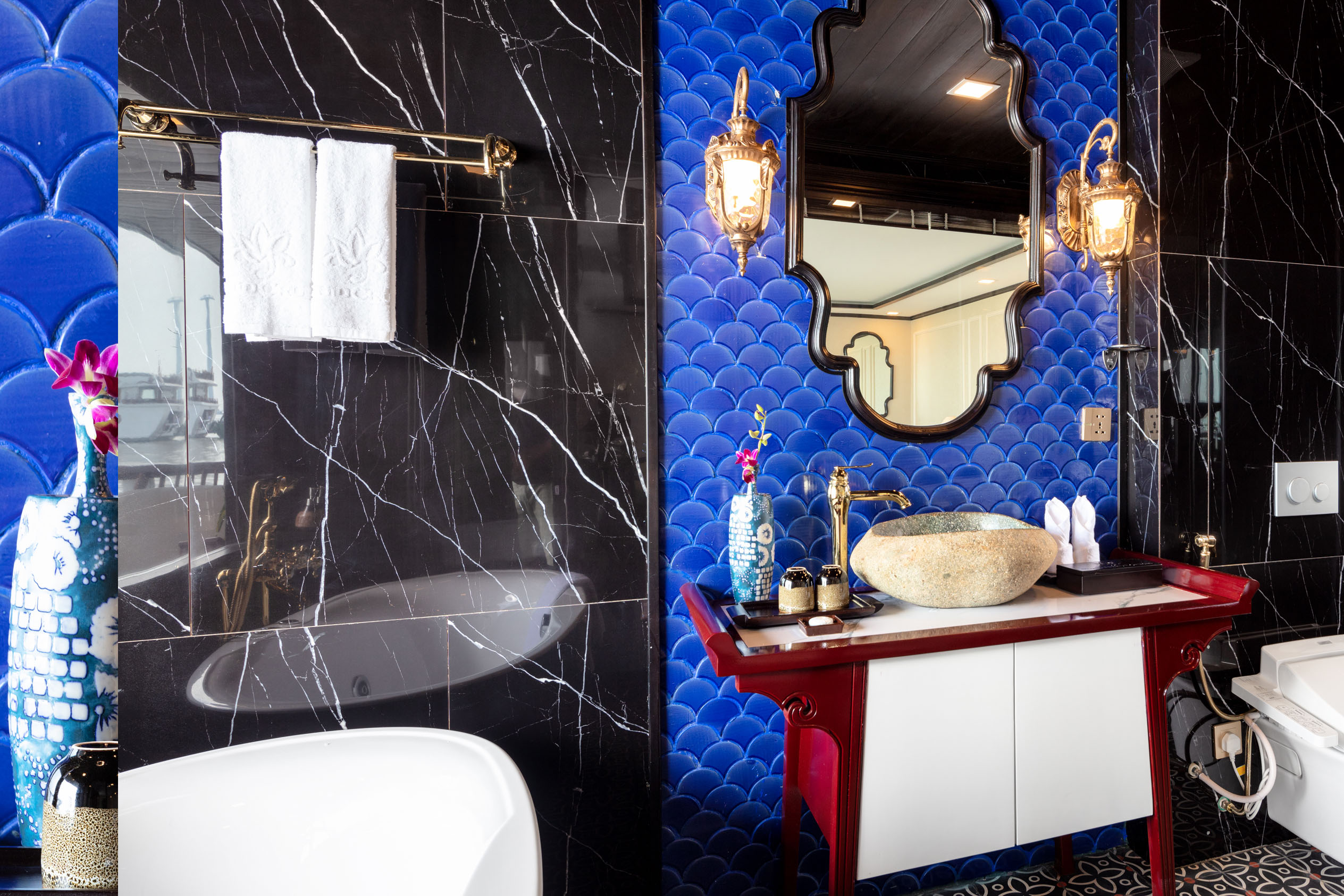 Luxurious hotel bathroom with blue scallop tiles and elegant black marble accents.