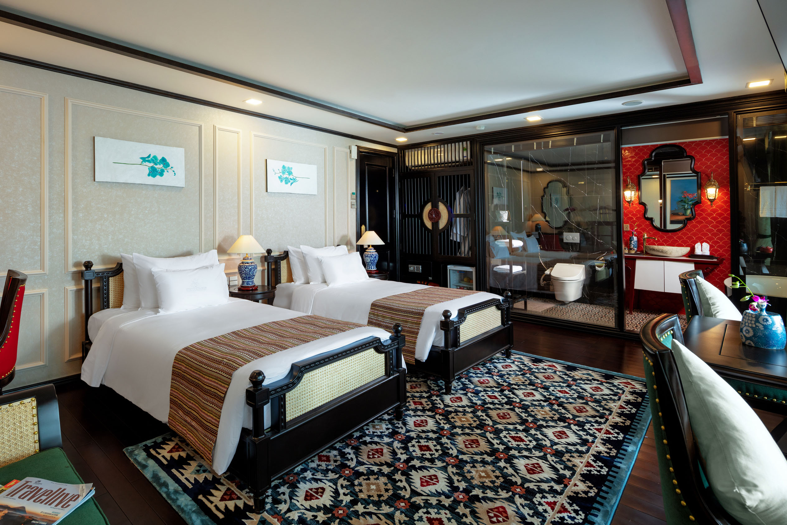 Elegantly decorated hotel room with two beds, stylish furniture, and a modern bathroom in a luxury setting.