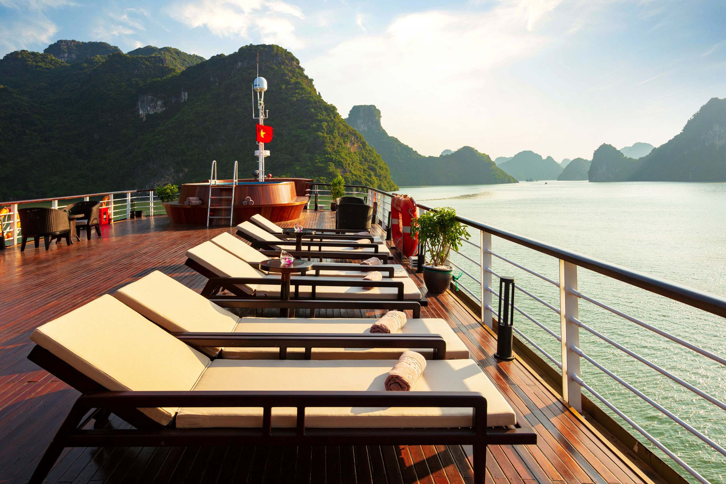 Relaxing cruise deck with sun loungers overlooking scenic limestone islands in Ha Long Bay, Vietnam.