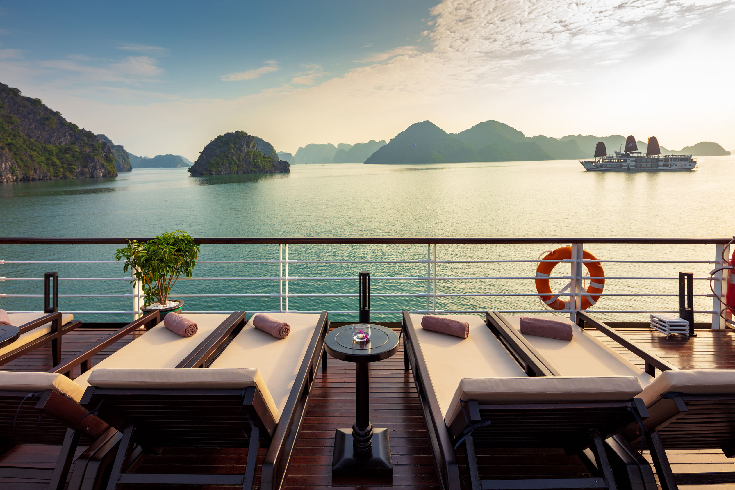 Relaxing cruise deck with sun loungers overlooking Ha Long Bay's scenic karst islands in Vietnam.