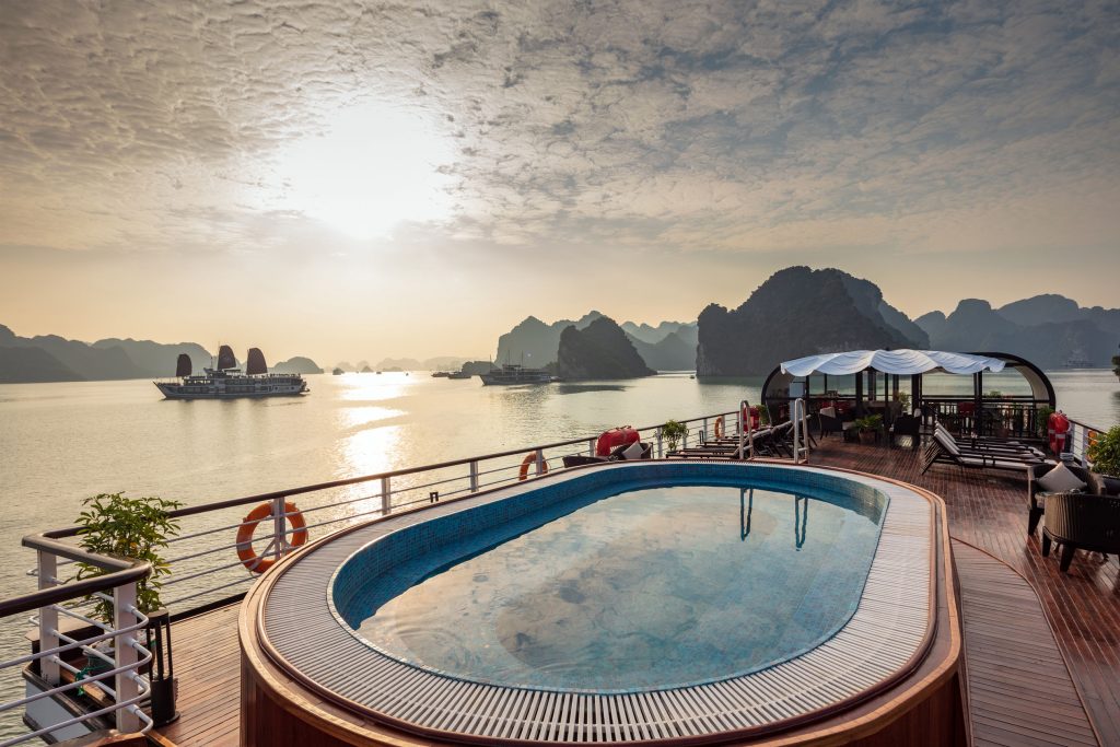 Luxury river cruise balcony with pool and scenic bay views at sunrise.