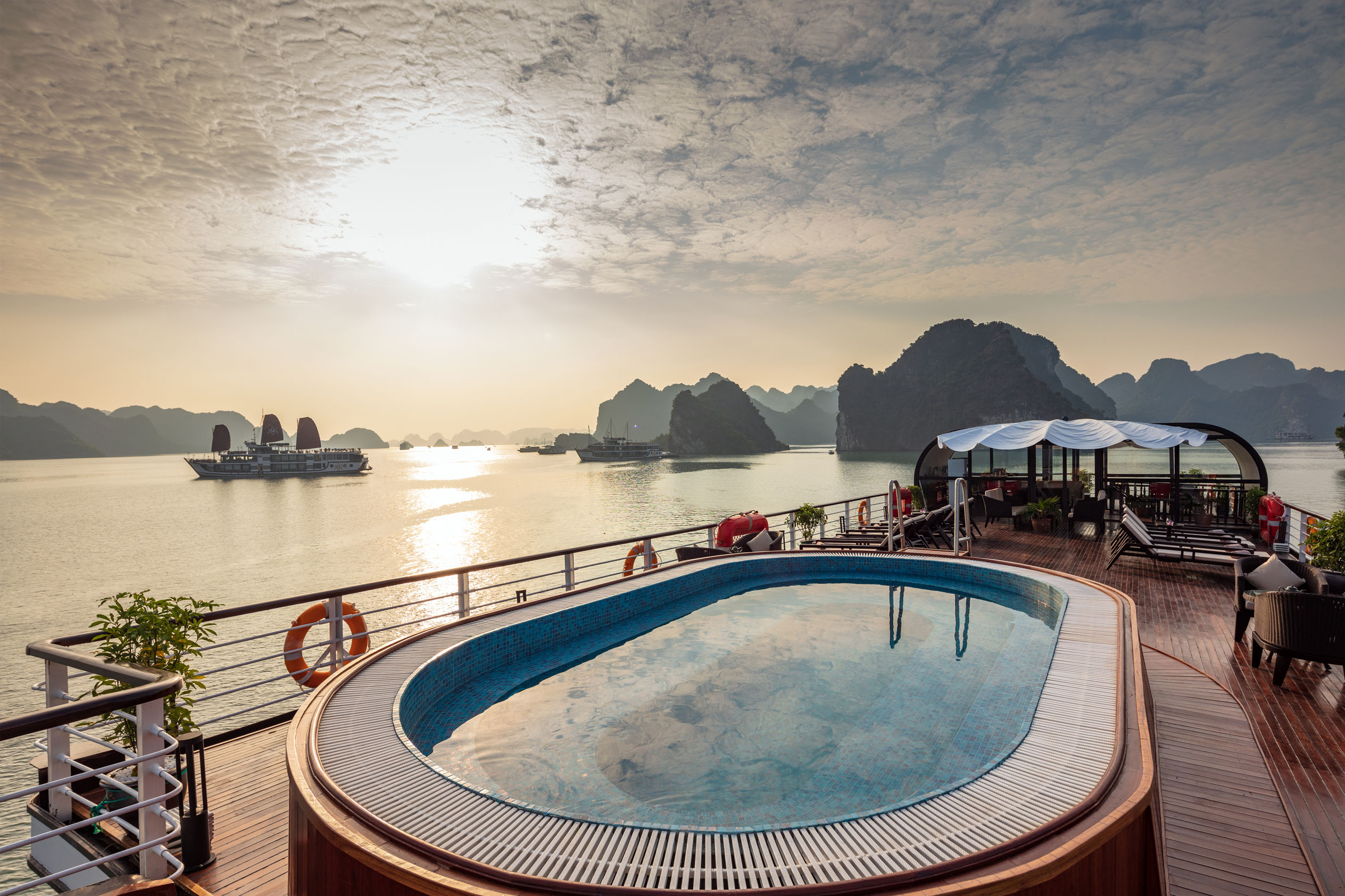 Luxury river cruise balcony with pool and scenic bay views at sunrise.