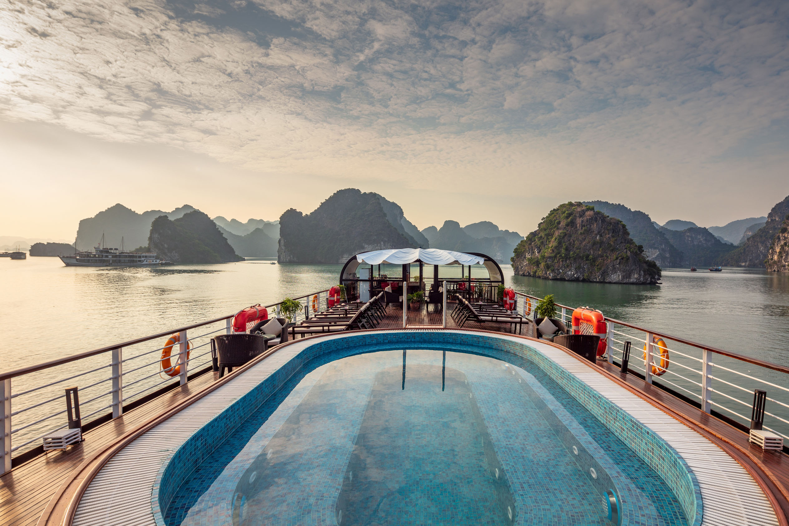 Luxury cruise ship with infinity pool and scenic karst islands in Halong Bay Vietnam.