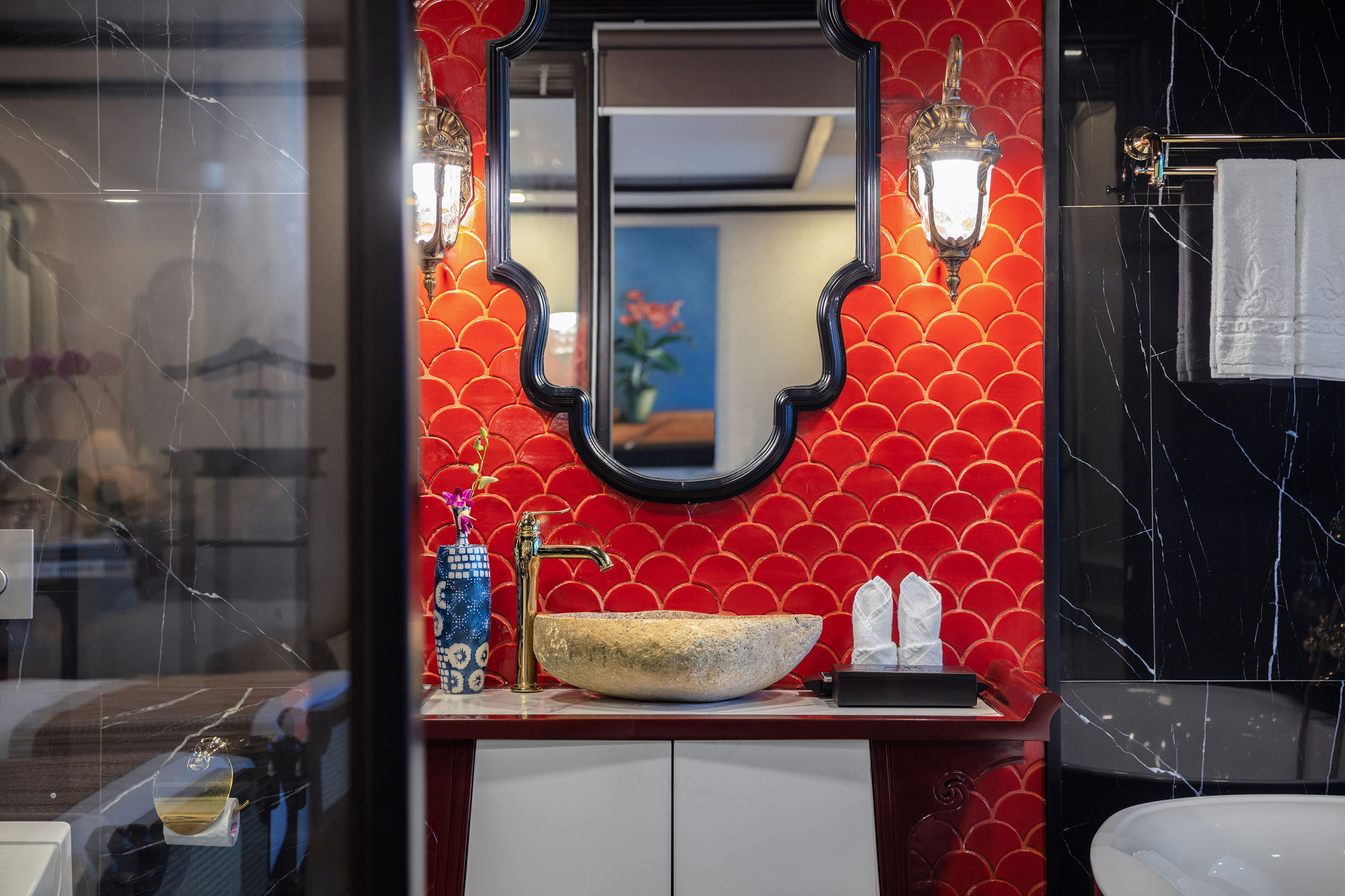 Luxurious bathroom with red patterned tiles, ornate mirror, and elegant lighting, showcasing Vietnamese interior design.
