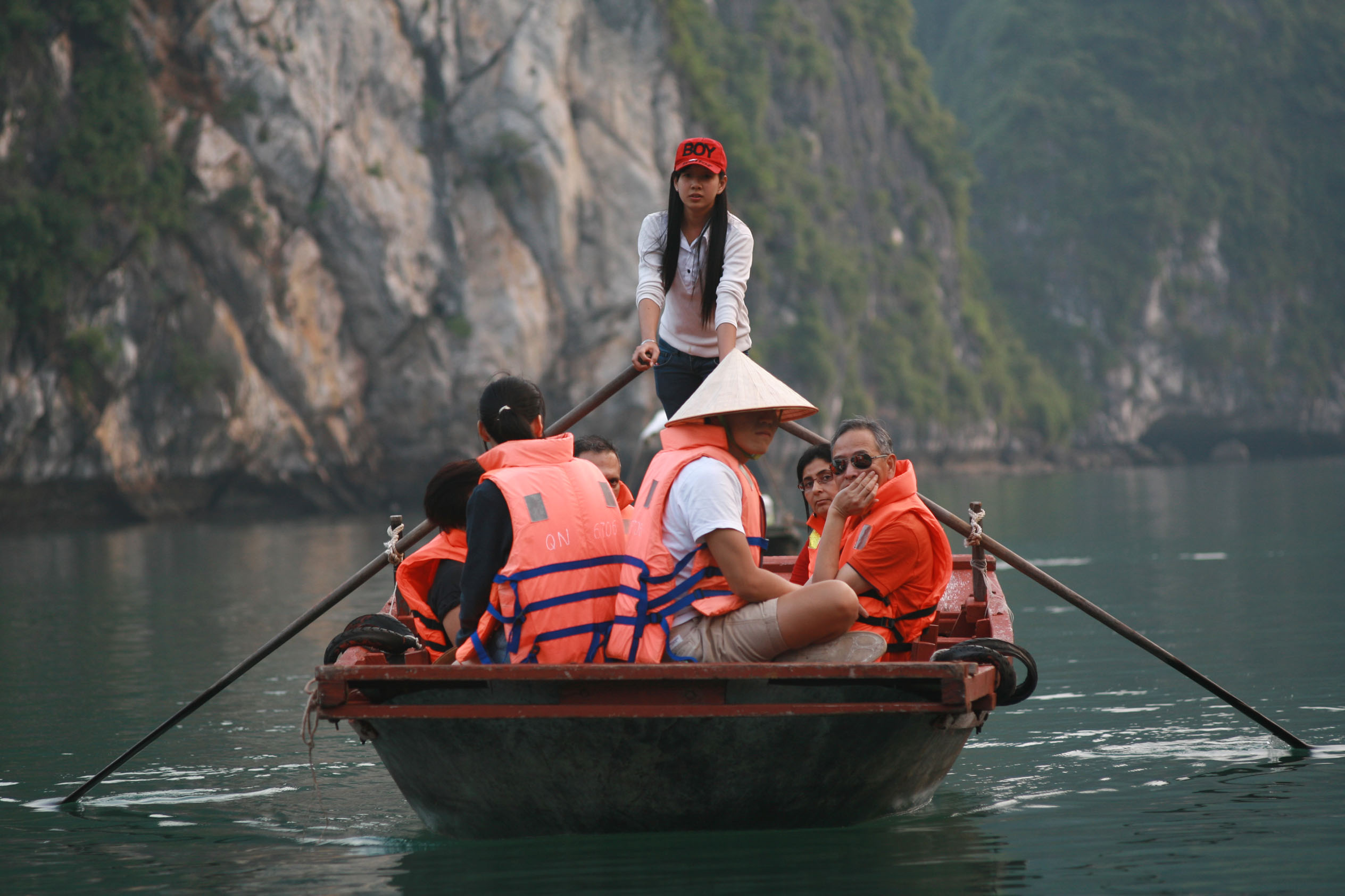 Boating tour on Halong Bay in Vietnam with tourists in a traditional wooden boat.
