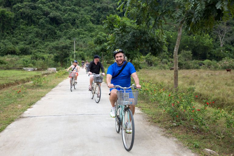 Scenic outdoor cycling tour in lush green countryside with smiling group of cyclists.