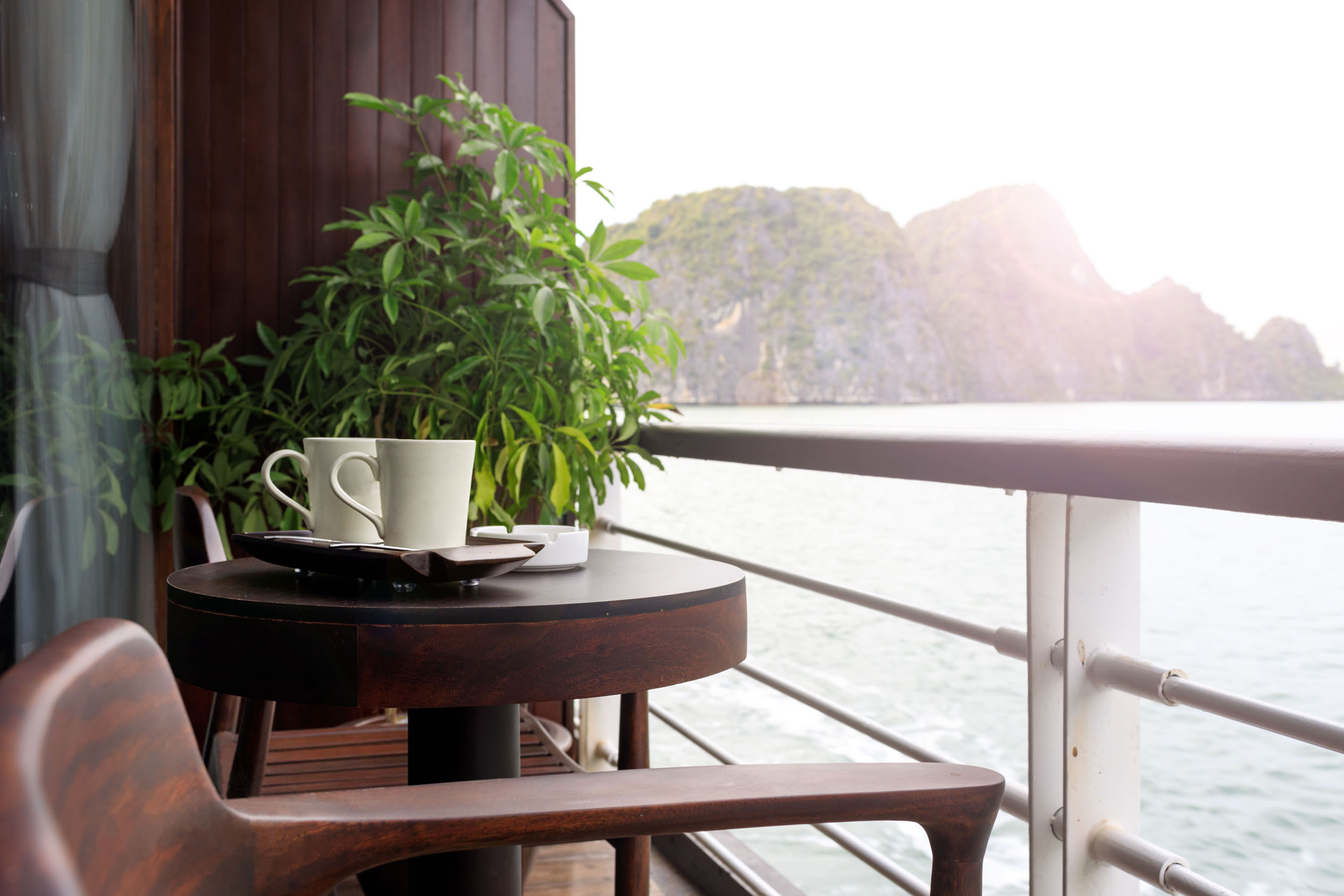 Stunning balcony view with tea cups overlooking Halong Bay, Vietnam, ideal for travel enthusiasts and scenic cruises.