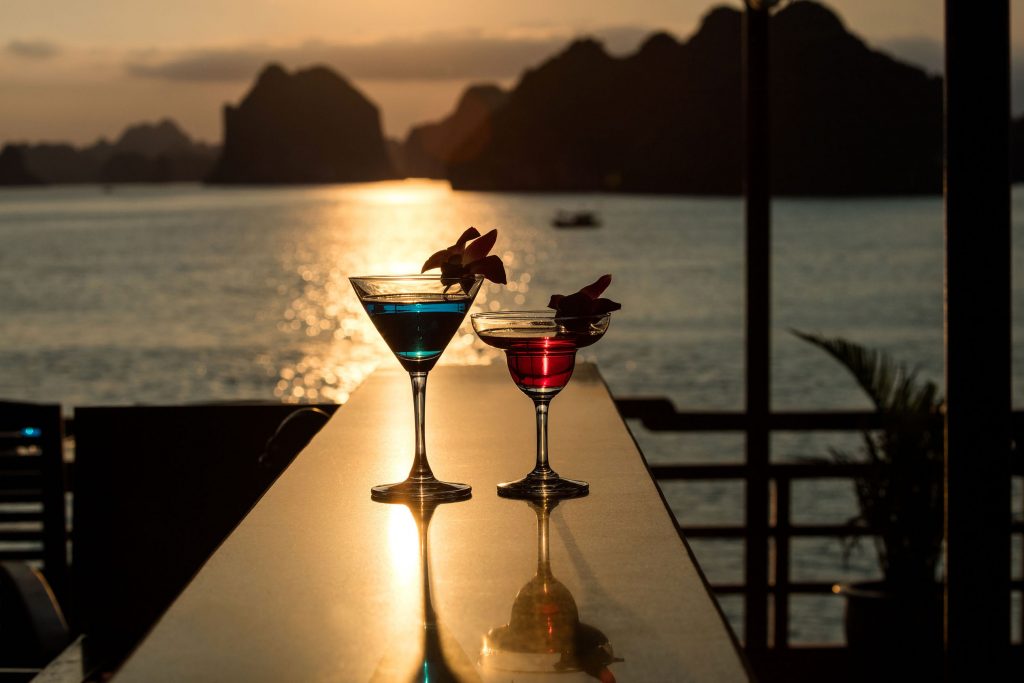 Colorful cocktails at sunset on a seaside balcony, tropical vacation drinks with ocean view.
