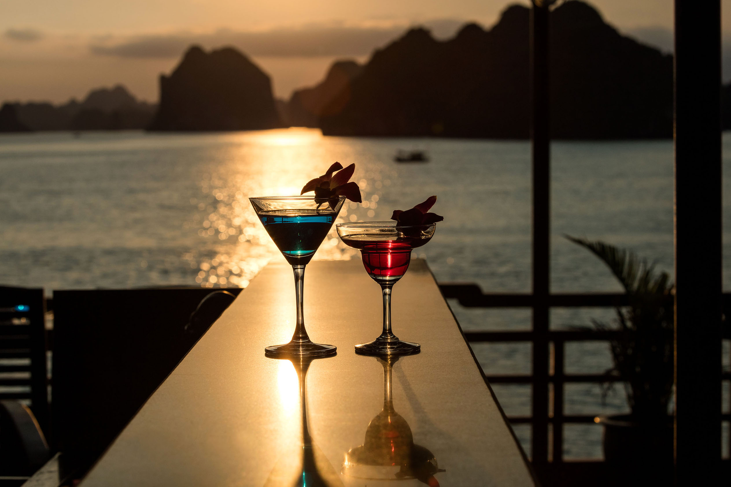 Colorful cocktails at sunset on a seaside balcony, tropical vacation drinks with ocean view.