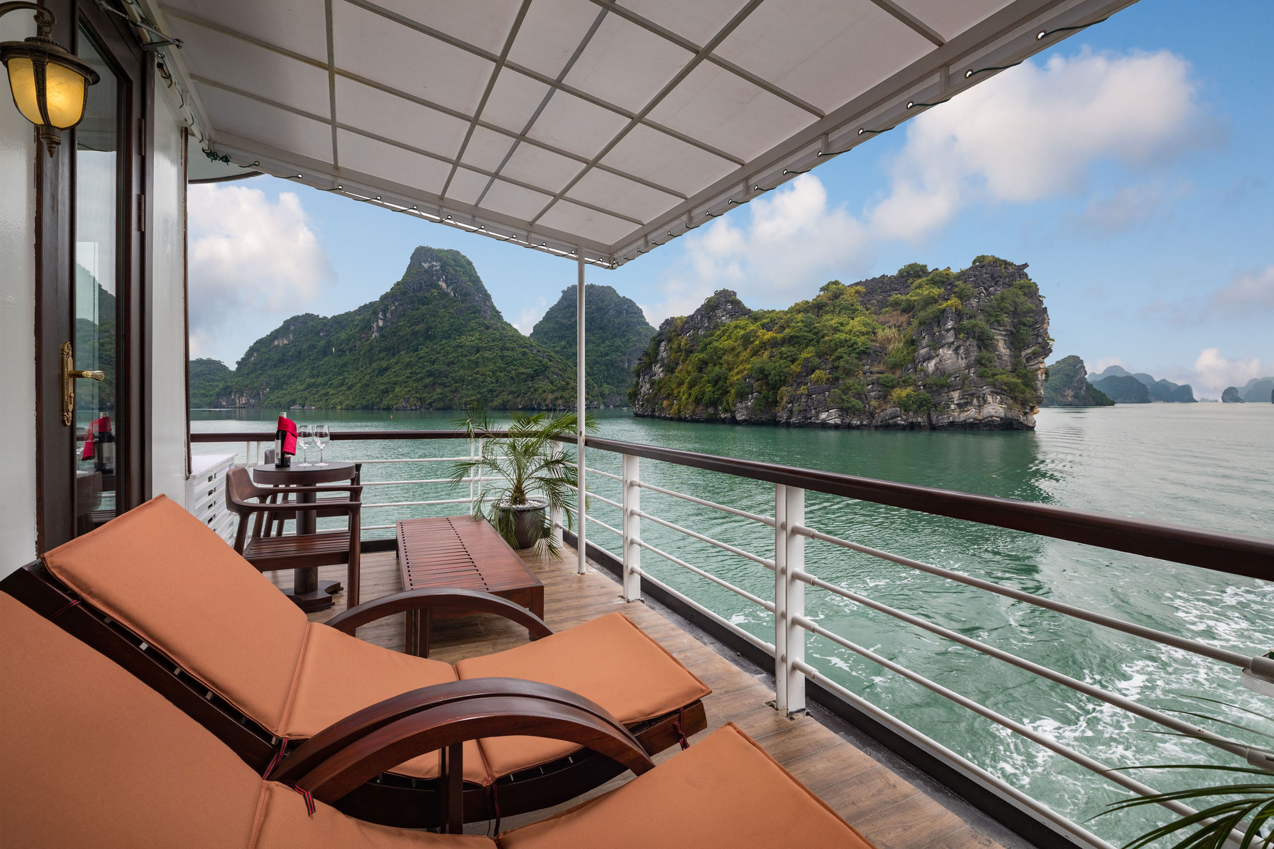 Breathtaking view of limestone islands from a luxury cruise balcony in Ha Long Bay, Vietnam.