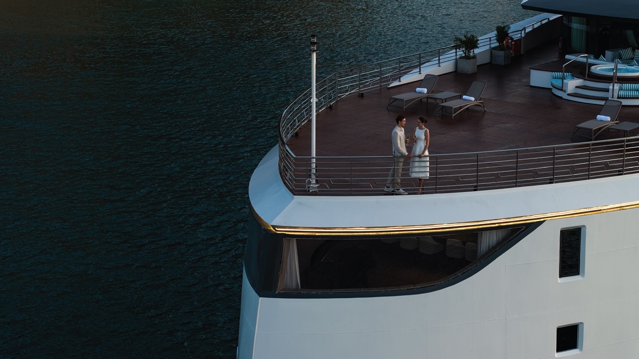 Romantic couple on luxury cruise deck with ocean view, ideal for honeymoons and leisure travel.