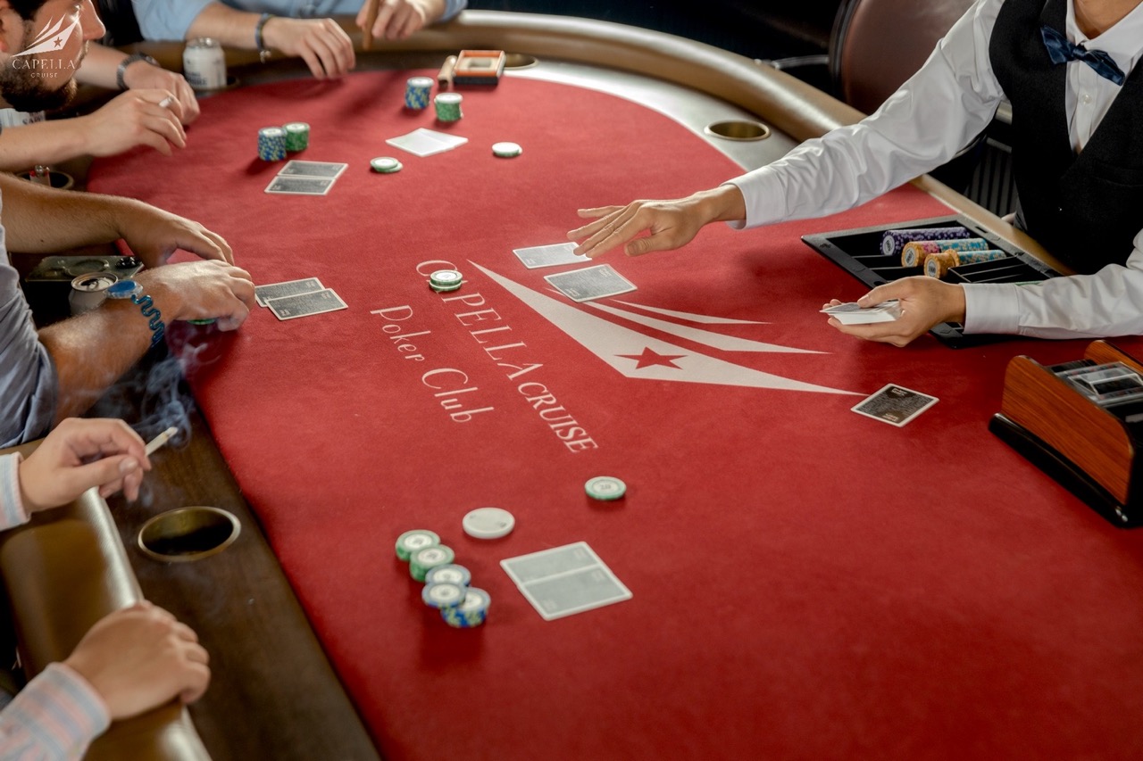 Exciting poker game at Delance Cruise Poker Club with players and dealer on a red felt table.