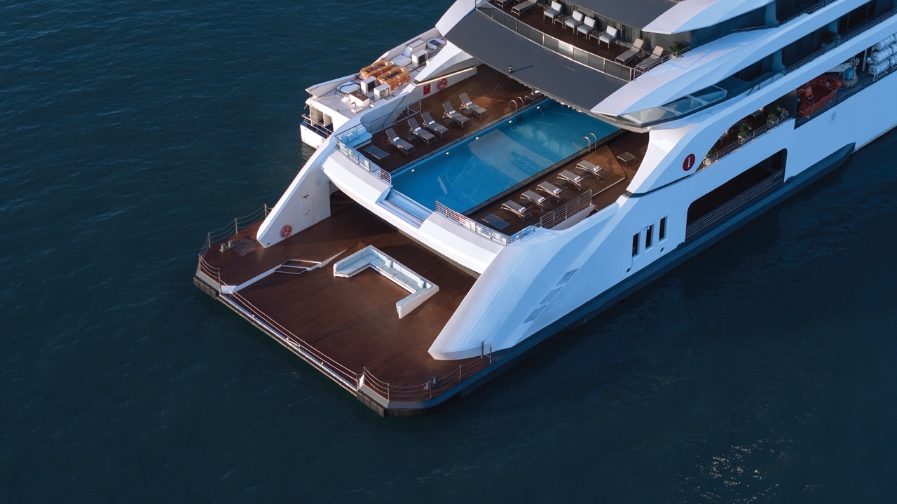 Luxurious yacht with pool and outdoor deck in crystal-clear water.