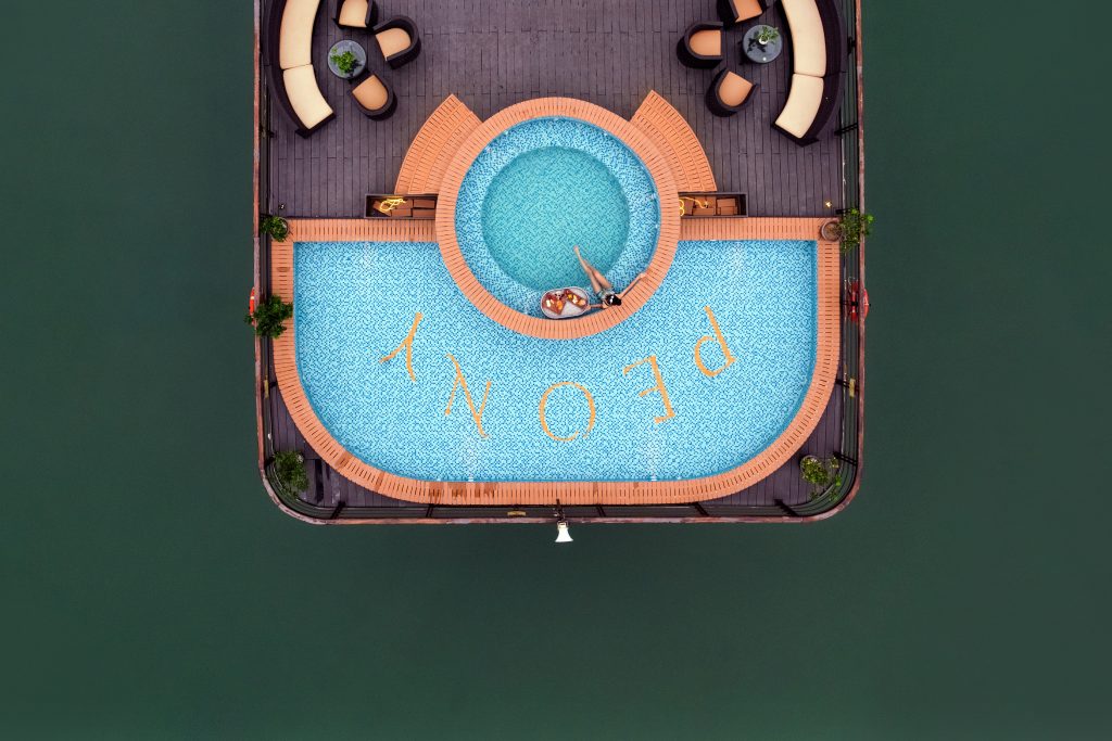 Aerial view of a luxurious swimming pool on a cruise in Halong Bay, with surrounding deck chairs and.