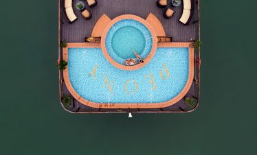 Aerial view of a luxurious swimming pool on a cruise in Halong Bay, with surrounding deck chairs and.