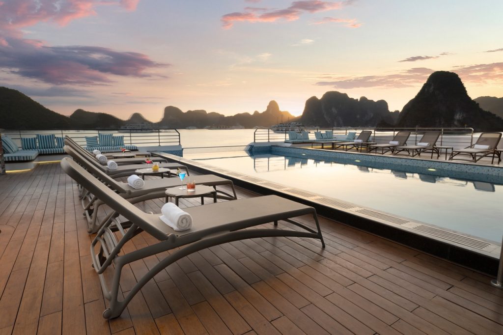 Luxurious rooftop pool with stunning sunset view over limestone islands in Vietnam.