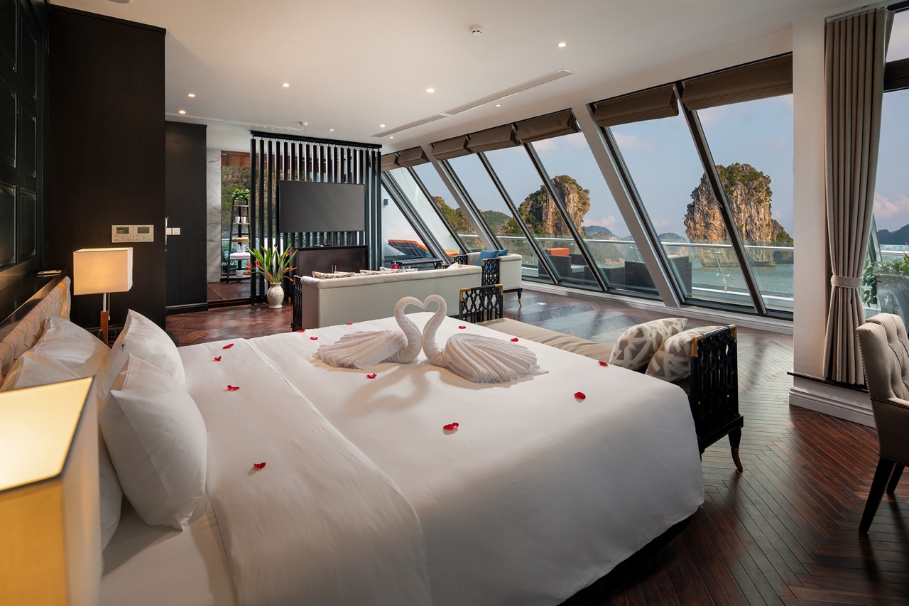 Luxurious ocean-view hotel suite with romantic towel art and stunning limestone karsts outside.