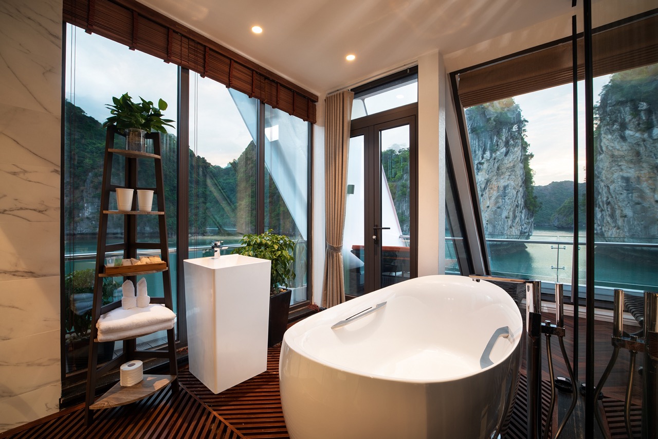 Luxury bathroom with bathtub overlooking scenic river and limestone cliffs in Vietnam.