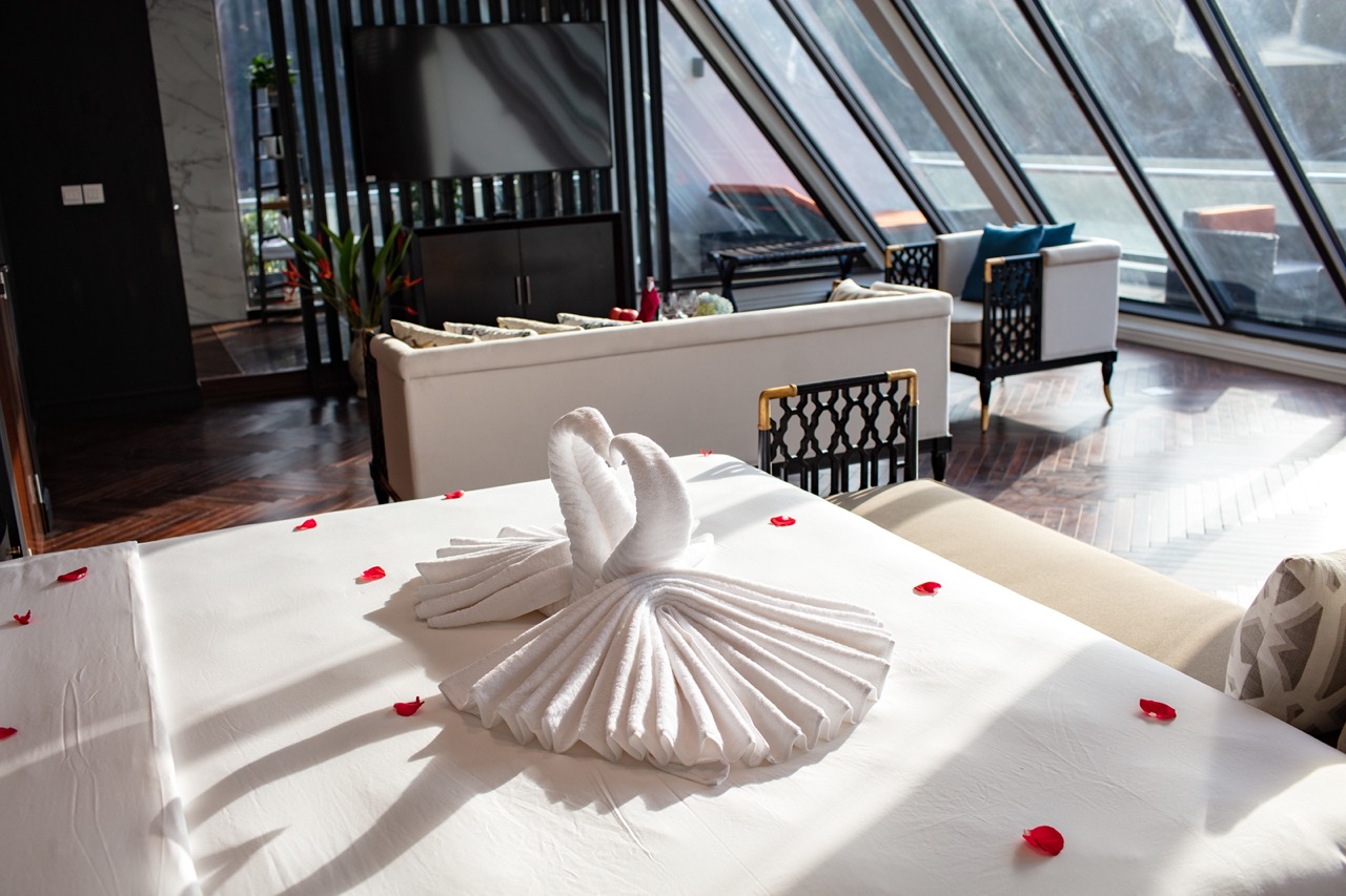 Luxurious hotel room with swan towel art and romantic decor for honeymoon or getaway.