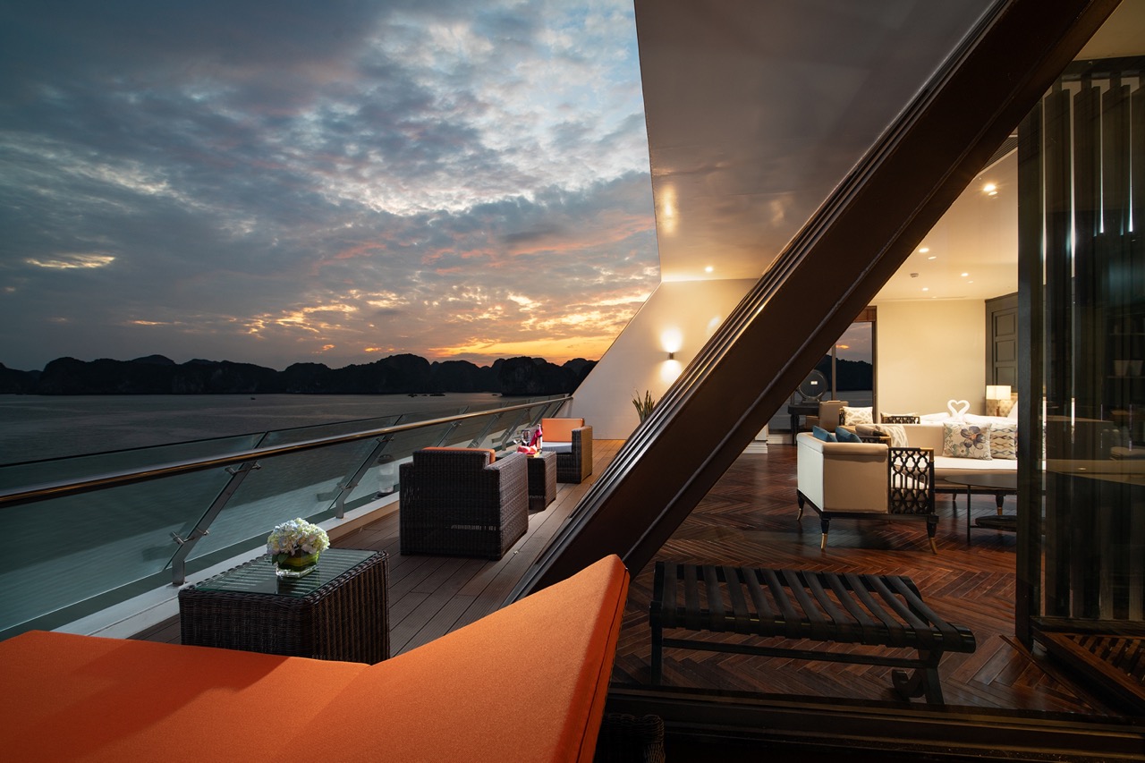Spectacular sunset view from a luxury cruise balcony overlooking picturesque islands and calm waters.
