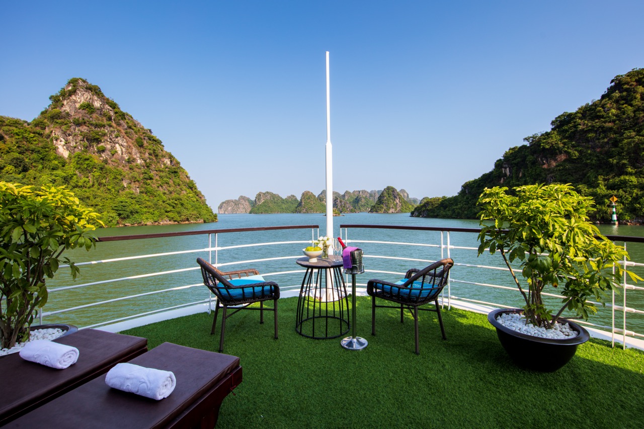 Stunning view from a cruise balcony in Halong Bay, showcasing emerald waters and limestone karsts, p.
