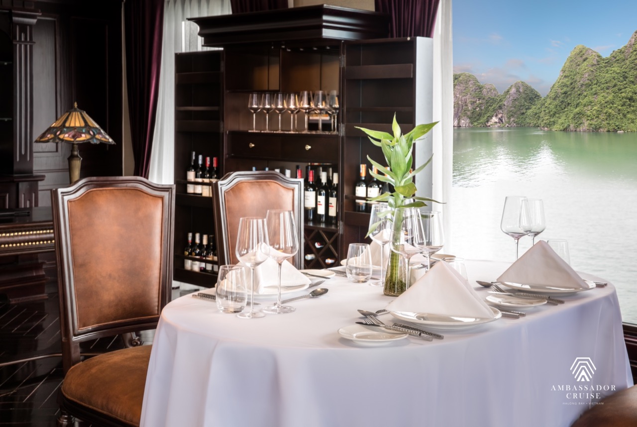 Elegant dining setup with scenic view of Halong Bay, perfect for luxury cruise travelers.