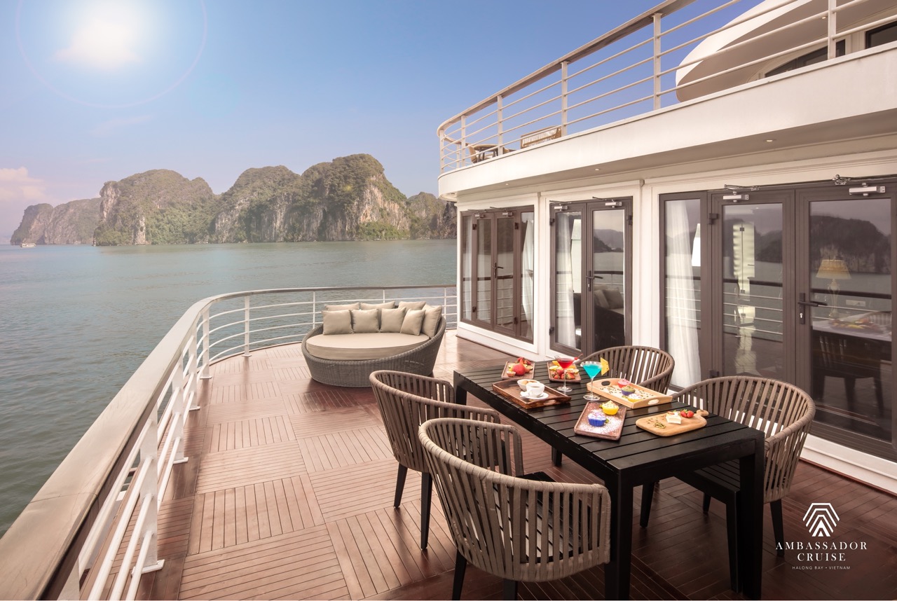 Stunning view from cruise balcony in Halong Bay with elegant dining setup and scenic limestone karst.