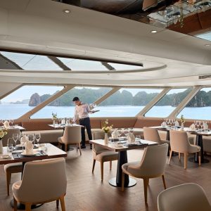Luxurious cruise dining room with ocean views and elegant table settings.