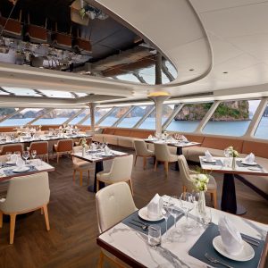 Luxurious cruise ship dining area overlooking ocean with modern decor and elegant table settings.