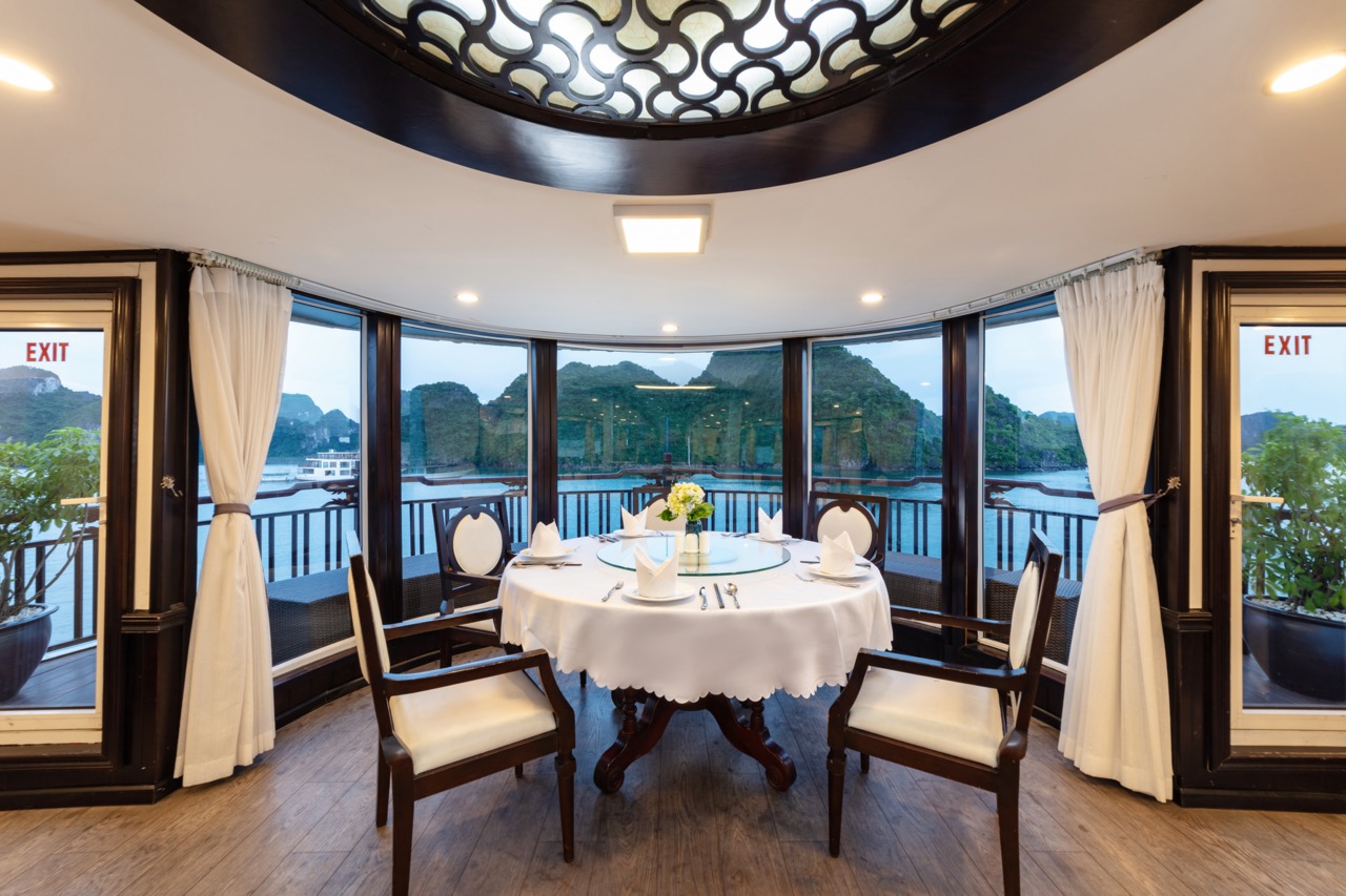 Elegant dining room with panoramic water views and mountain landscape in Vietnam.