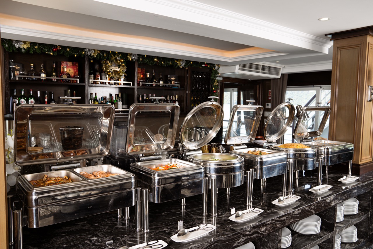 Buffet station on a luxury Halong Bay cruise with diverse dishes and scenic backdrop.