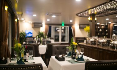 Luxurious cruise dining scene with table settings and ambient lighting in Halong Bay.