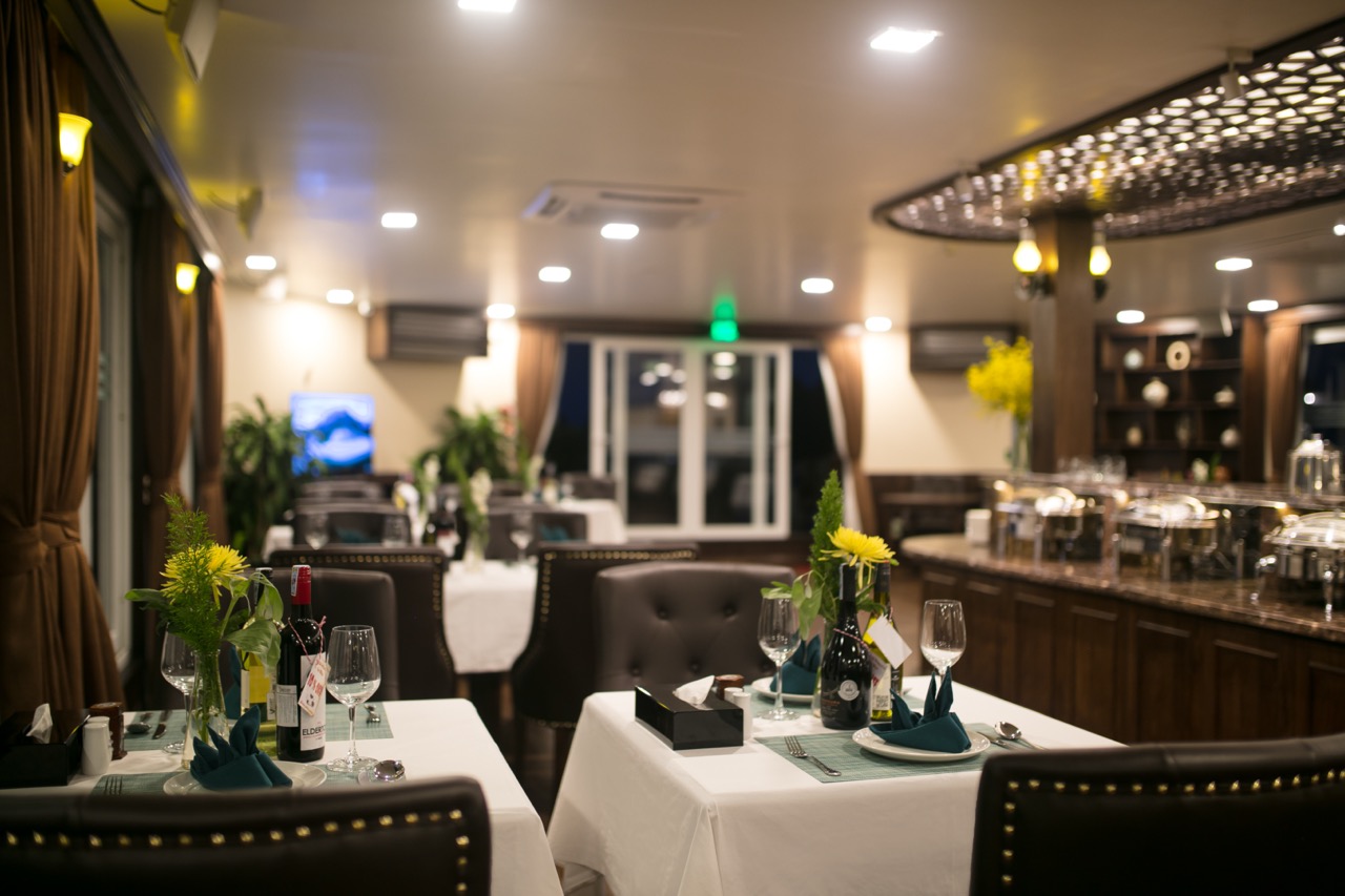 Luxurious cruise dining scene with table settings and ambient lighting in Halong Bay.