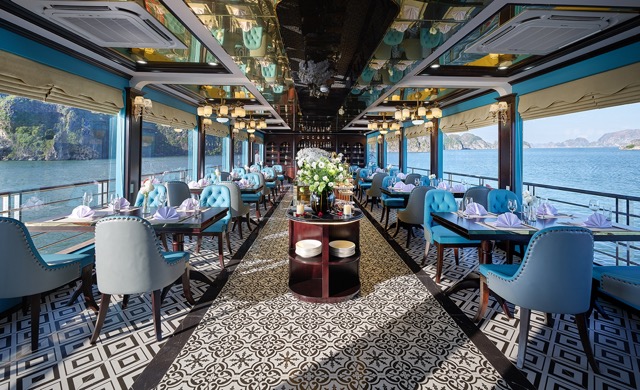 Stunning cruise balcony view of Halong Bay with elegant dining setup and scenic water landscape.