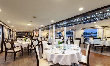 Luxurious yacht restaurant interior with elegant dining setup and scenic waterfront views.