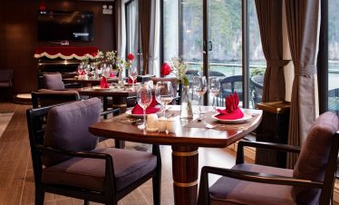 Luxurious restaurant dining with lake views, elegant table setting, and red accents for romantic meals.