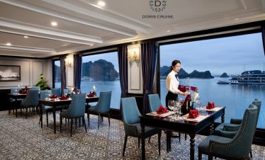 Stunning view of Halong Bay from cruise balcony with elegant dining setup and scenic limestone karst.