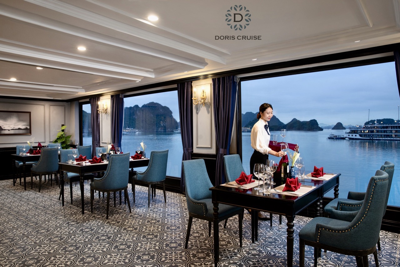 Stunning view of Halong Bay from cruise balcony with elegant dining setup and scenic limestone karst.