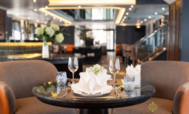 Elegant dining setup on Halong Bay cruise balcony with scenic views.