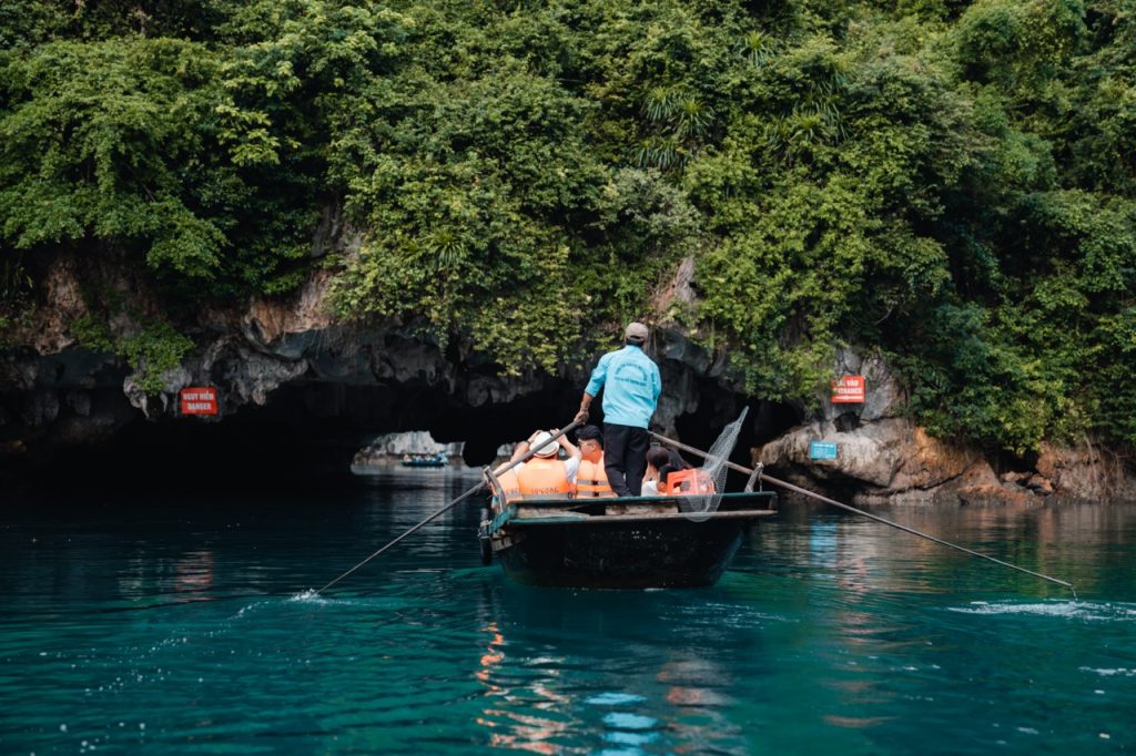Scenic view of a cruise boat navigating through the emerald waters of Halong Bay, surrounded by lush.