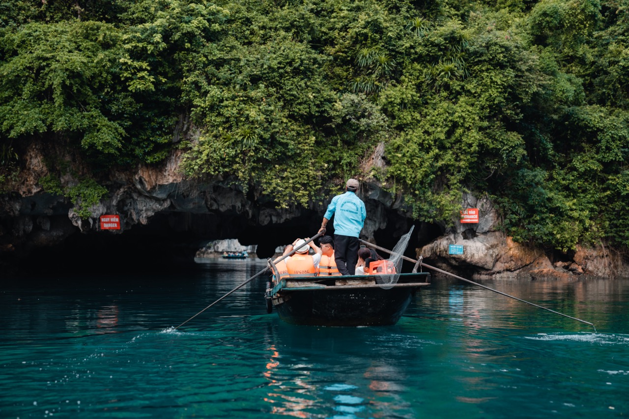 Scenic view of a cruise boat navigating through the emerald waters of Halong Bay, surrounded by lush.