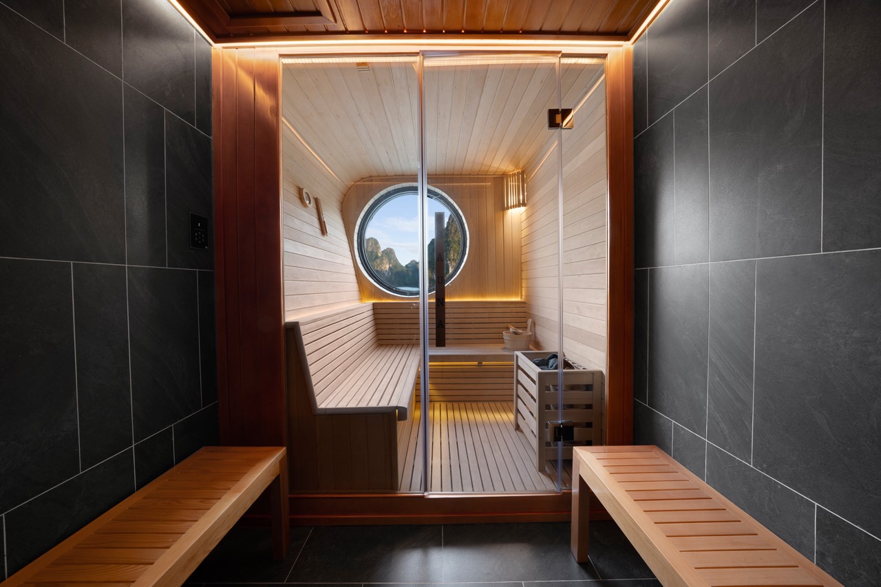 Relaxing sauna with wooden interiors and mountain view through round window.
