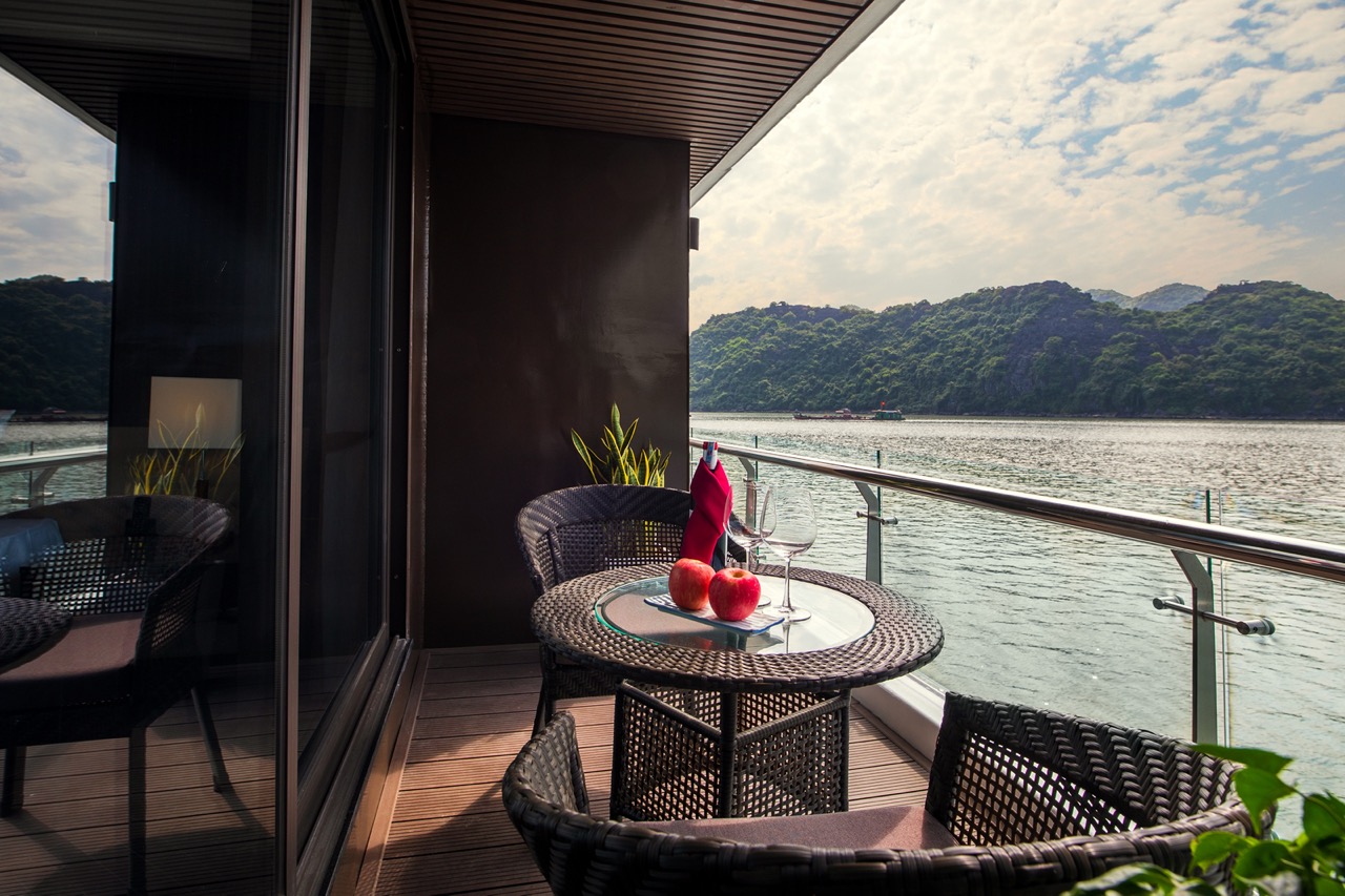 Serene balcony with river view, outdoor dining setup, and lush green islands in the background.