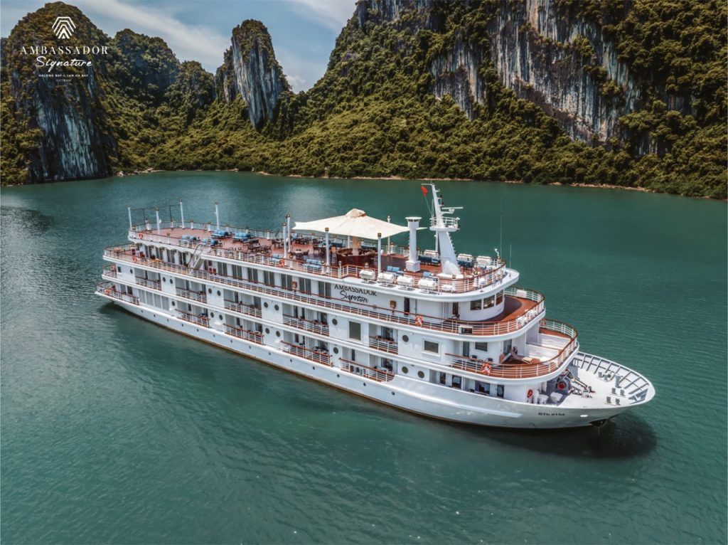 Stunning Halong Bay cruise scene with lush green karst islands and calm emerald waters.
