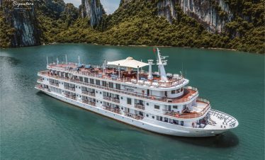 Stunning Halong Bay cruise scene with lush green karst islands and calm emerald waters.