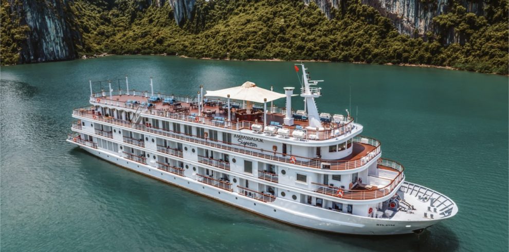 Stunning Halong Bay cruise scene with lush green karst islands and calm emerald waters.