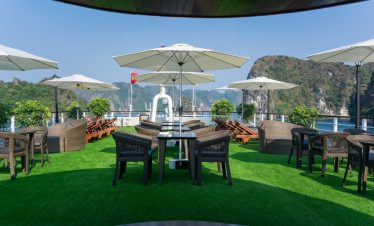 Relaxing cruise balcony with umbrellas and scenic views of Halong Bay.