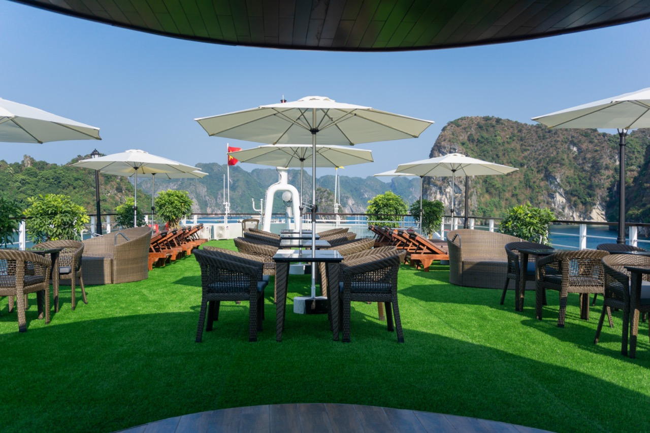 Relaxing cruise balcony with umbrellas and scenic views of Halong Bay.