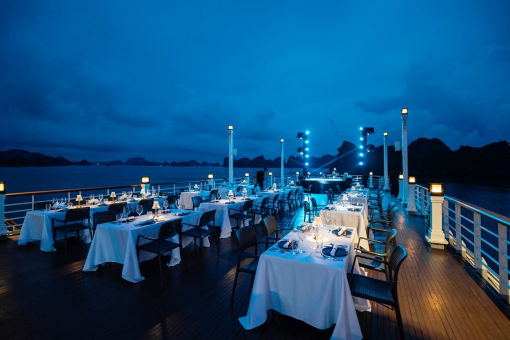 Elegant cruise balcony dining experience on Halong Bay at sunset, perfect for romantic travel and sc.