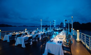 Elegant cruise balcony dining experience on Halong Bay at sunset, perfect for romantic travel and sc.